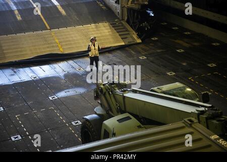 NORFOLK (July 25, 2017) Boatswain's Mate 2nd Class Ivana Catsaldi guides United States Marine Corps vehicles as they are loaded onto a landing craft air cushion (LCAC) during a loading exercise (LOADEX) aboard the amphibious transport dock ship USS Arlington (LPD 24). The exercise is designed to train Sailors amd Marines with rapid response capabilities to support recovery efforts and assist local authorities following man-made and natural disaster. Stock Photo