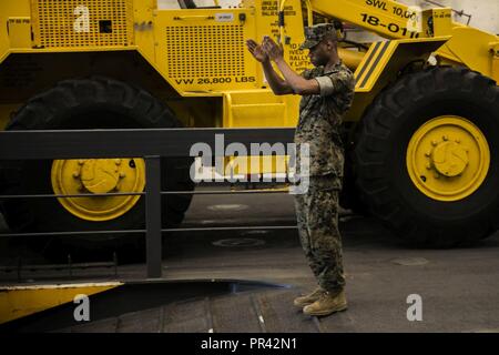 NORFOLK (July 25, 2017) Staff Sgt. Kristian Mitchell guides United States Marine Corps equipment as it is loaded onto a landing craft air cushion (LCAC) aboard the amphibious transport dock ship USS Arlington (LPD 24) during a loading exercise (LOADEX). The exercise is designed to train Sailors amd Marines with rapid response capabilities to support recovery efforts and assist local authorities following man-made and natural disaster. Stock Photo