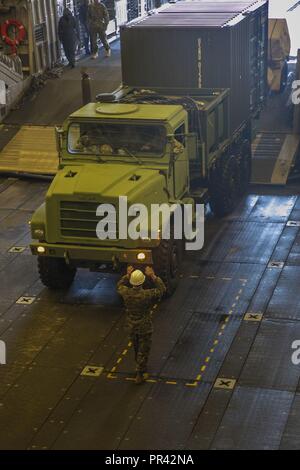 NORFOLK (July 25, 2017) Chief Warrant Officer Kregg Rickert guides United States Marine Corps vehicles as they are loaded onto a landing craft air cushion (LCAC) during a loading exercise (LOADEX) aboard the amphibious transport dock ship USS Arlington (LPD 24). The exercise is designed to train Sailors amd Marines with rapid response capabilities to support recovery efforts and assist local authorities following man-made and natural disaster. Stock Photo