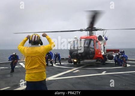 Coast Guard Petty Officer 1st Class Sean Carrillo signals to crew members during helicopter operations onboard the Coast Guard Cutter Healy while on patrol off the coast of Alaska, July 28, 2017. The Coast Guard has a long history of Arctic operations and possesses unique capabilities to ensure the region is stable, secure, and developed in a sustainable manner. Coast Guard Stock Photo