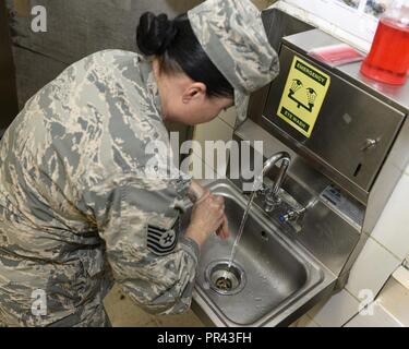 U.S. Air Force Technical Sgt. Alina Ness, non-commissioned officer of food safety and sanitation assigned to the Public Health Element of the 379th Expeditionary Medical Group, washes her hands during an inspection of a dining facility at Al Udeid, Air Base, Qatar, July 22, 2017. The members of the 379th EMDG/SGOL work behind the scenes to help keep Airmen deployed here healthy by inspecting public facilities, ensuring the medical readiness of forward deploying Airmen and by tracking and working to prevent the spread of communicable diseases. Stock Photo