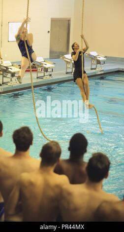 Hannah Aspden (left), an athlete of the Royals Swimming Team at the Queens University of Charlotte, and Capt. Kellie Mix, a Marine Corps Instructor of Water Survival, participate in a rope-climb and pull-up challenge after Marine Corps water survival training during United States Marine Corps’ 2018 Marine Week in Charlotte, North Carolina, September 6, 2018. Marines are inherently amphibious by nature and are expected to operate in aquatic environments. Marine Corps water survival training’s purpose is to reduce fear, raise self- confidence, and develop Marines with the ability to survive in w Stock Photo