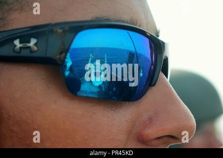 GULF OF OMAN (Sept. 8, 2018) Gunner’s Mate 2nd Class Dante Johnson’s sunglasses show a reflection of the orange 'killer tomato' inflatable target used for a live fire exercise aboard the guided-missile destroyer USS The Sullivans (DDG 68). The Sullivans is deployed to the U.S. 5th Fleet area of operations in support of naval operations to ensure maritime stability and security in the Central Region, connecting the Mediterranean and the Pacific through the western Indian Ocean and three strategic choke points. Stock Photo