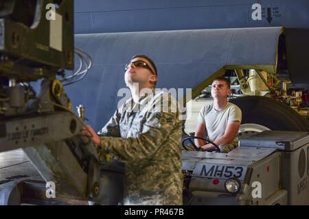 From left, Airmen 1st Class Kevin Lewis and Ryan Burleson, 5th Aircraft Maintenance Squadron load crew team members, align an inert munition during a bomb loading competition at Minot Air Force Base, North Dakota, Sept. 7, 2018. Two weapons load crews, representing the 23rd and 69th Bomb Squadrons, were timed on their ability to efficiently load an inert munition onto a B-52H Stratofortress. Stock Photo