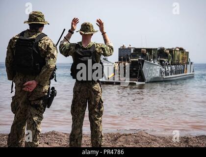 DJIBOUTI (Sept. 8, 2018) Engineman Fireman Cory Durenberger, assigned to Beach Master Unit (BMU) 1, signals a landing craft utility while participating in Theater Amphibious Combat Rehearsal (TACR) 18. Led by Naval Amphibious Force, Task Force 51/5th Marine Expeditionary Brigade, TACR integrates U.S. Navy and Marine Corps assets to practice and rehearse a range of critical combat-related capabilities available to U.S. Central Command, both afloat and ashore, to promote stability and security in the region. U.S. 5th Fleet and coalition assets are participating in numerous simultaneous exercises Stock Photo