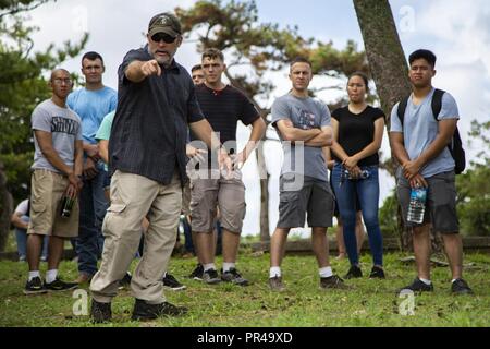 Chris Majewski points to a Japanese offensive position during a tour Sept. 7, 2018 at Hacksaw Ridge, Okinawa, Japan. Marines and Sailors with Headquarters Company, Headquarters Regiment, 3rd Marine Logistics Group, participated in the World War II battle site tour to learn about the U.S. Marine Corps’ history on Okinawa and remember those who have gone before them. Majewski is a tour guide with Marine Corps Community Services Tours+ and is a native of Boulder City, Nevada. Stock Photo