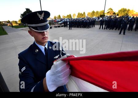 An Airman holds the flag as it is raised then lowered to half-staff during the 9/11 reveille formation at Schriever Air Force Base, Colorado, Sept. 11, 2018. More than 50 Airmen stood in formation for reveille during the event. Stock Photo