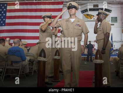 PHILIPPINE SEA (Sep. 14, 2018) Chief Boatswain’s Mate Juan Vigil, from Las Vegas, passes through the sideboys during a chief pinning ceremony in the hangar bay of the aircraft carrier USS Ronald Reagan (CVN 76). The ceremony is part of a long-standing tradition that honors and recognizes the years of hard work, service, and leadership of dedicated Sailors in the Navy. Ronald Reagan is forward-deployed to the U.S. 7th Fleet area of operations in support of security and stability in the Indo-Pacific region. Stock Photo