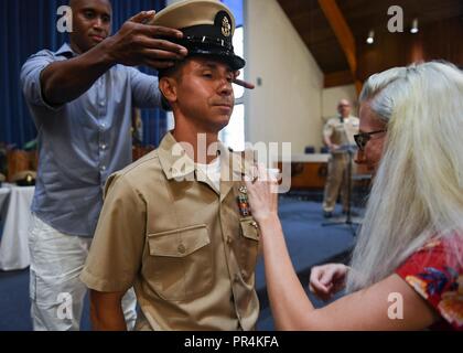 PEARL HARBOR (Sept. 14, 2018) Chief Yeoman Marcell Denkewalter is pinned and receives his chief combination cover by his family members during a chief petty officer pinning ceremony at the Hickam Chapel on Joint Base Pearl Harbor-Hickam, Sept. 14. The ceremony recognized 20 newly-pinned chiefs assigned to the Hawaii region. Stock Photo