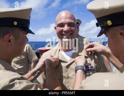 PHILIPPINE SEA (Sept. 16, 2018) Chief Sonar Technician William Imfeld receives his chief collar devices during a chief pinning ceremony aboard the the Arleigh Burke-class guided-missile destroyer USS Shoup (DDG 86). The ceremony is part of a long-standing tradition that honors and recognizes the years of hard work, service and leadership of dedicated Sailors in the Navy. Shoup is forward-deployed to the U.S. 7th Fleet area of operations in support of security and stability in the Indo-Pacific region. Stock Photo
