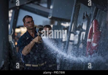 SEA (Sept. 16, 2018) Chief Boatswain’s Mate Dante Sartini washes the Arleigh Burke-class guided-missile destroyer USS Carney (DDG 64) Sept. 16, 2018. Carney, forward-deployed to Rota, Spain, is on its fifth patrol in the U.S. 6th Fleet area of operations in support of regional allies and partners as well as U.S. national security interests in Europe and Africa. Stock Photo