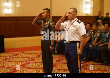 Hawaii National Guard State Partnership Program Coordinator, Capt. Marco Hartanto and TNI Maj. Indra Ardiansyah offer up the first salute during marking the official start of the staff exercise, Sept. 17, 2018, Jakarta Indonesia. Gema Bhakti is a joint force multi-national staff exercise where military staff from the U.S. Indo-Pacific Command and Indonesia work through a process known as the military decision making process. This process is a crucial step that involves the commander’s staff working with with all the higher and lower commands to define the mission, its variables, and the situat Stock Photo