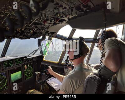 Alaska Air National Guardsmen from the 176th Wing’s 211th Rescue Squadron scan the horizon looking for isolated flood survivors aboard an HC-130J Combat King II aircraft while assisting with hurricane relief operations in North Carolina, Sept. 17, 2018. Stock Photo