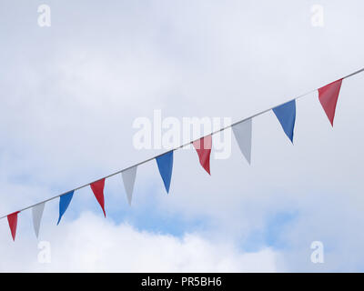 Red, white and blue festive bunting flags against sky background. Triangle shapes. Stock Photo