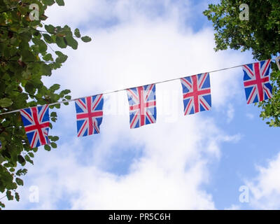Red, white and blue festive bunting flags against sky background. Union Jack, UK flags. Brexit maybe. Stock Photo