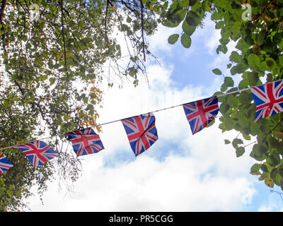 Red, white and blue festive bunting flags against sky background. Union Jack, UK flags blowing in the wind. Brexit maybe. Stock Photo