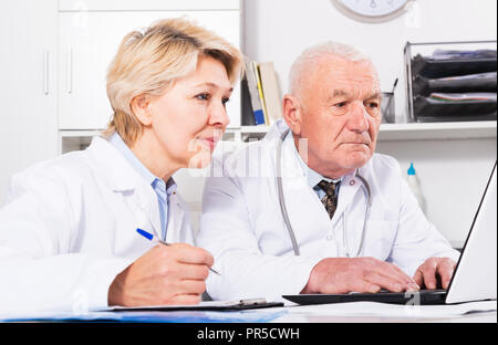 Adult male doctor and female nurse working effectively in clinic office Stock Photo