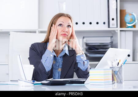 Frustrated business woman sitting at office desk with notebook Stock Photo