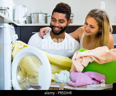 Happy smiling young mixed spouses doing regular laundry at home Stock Photo