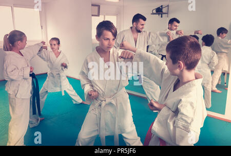 Serious positive teenagers practicing new karate moves in pairs in class Stock Photo