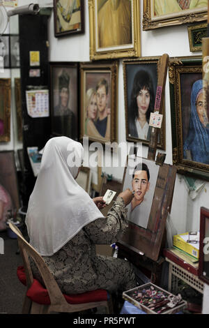Female portrait artist working from photograph in the Central Market, Chinatown, Kuala Lumpur, Malaysia Stock Photo