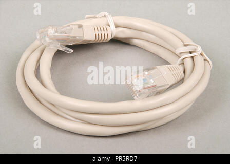 Patch cord grey network cable with molded RJ45 plug, isolated on a grey background Stock Photo