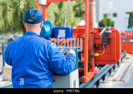 Worker pressing buttons on CNC machine control board in factory Stock Photo
