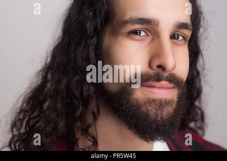 Closeup portrait of handsome confident man with black long curly hair and beard, looking at camera and smiling. male healthcare and beauty concept. in Stock Photo