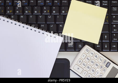 Calculator, smartphone and tablet on the laptop keyboard, close-up Stock Photo