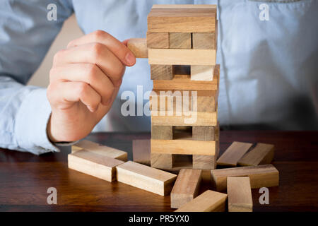 hand of businessman pulling out or placing wood block on tower Stock Photo