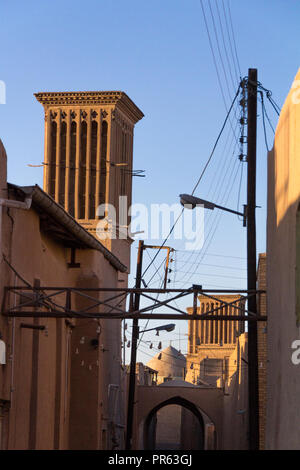 typical Windtower made of clay taken in the streets of Yazd, iran, surrounded by power electrical lines. These towers, aimed at cooling down buildings Stock Photo