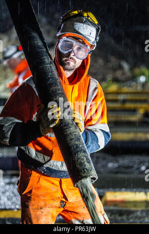 Railway construction workers pouring cement at night Stock Photo