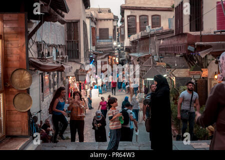 Damascus,Syria: night photo of a narrow alley in the old city near the Umayyad Mosque with people walking under the street lights. Stock Photo