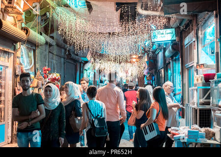 Damascus,Syria: night photo of a narrow alley in the old city near the Umayyad Mosque with people walking under the street lights. Stock Photo