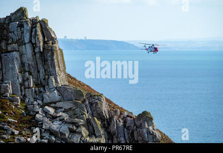HM Coastguard rescue helicopter G-MCGY during a rescue operation on the rugged granite coast of Lundy island off the North Devon coast UK Stock Photo