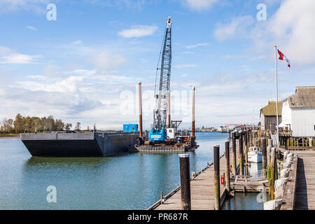 Floating dredging platform with a debris barge alongside in the community of Steveston, British Columbia Stock Photo