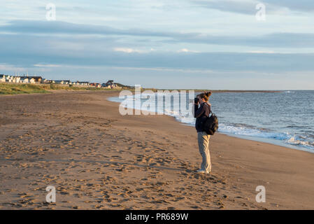 A photographer takes pictures in the early morning light at Winthorpe, near Skegness, UK Stock Photo