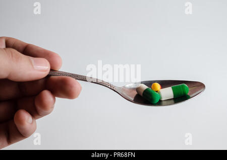 Spoon with pills on an isolated white background, concept of breakfast medicines. Stock Photo