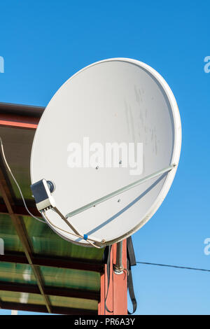Large gray satellite dish antenna on the garden house pillar Stock Photo