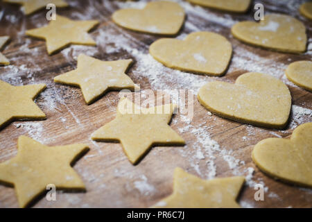 Christmas baking. Making gingerbread biscuits. Cookie dough in heart and star shape on kitchen counter. Stock Photo