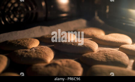 Christmas cookies baking in the oven. Christmas baking. Gingerbread biscuits on baking tray. Stock Photo