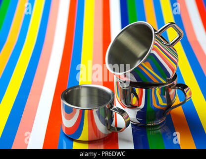 Metallic cups reflecting a colorful striped background. Stock Photo