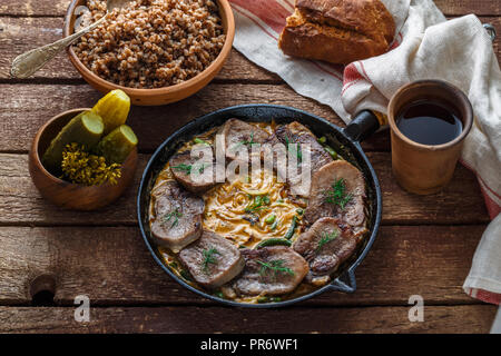 Fried beef tongue with creamy sauce, bread and pickles, rustic style Stock Photo