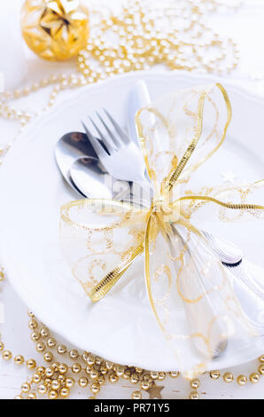 Table setting for celebration Christmas and New Year Holidays on white wooden table.. Festive place setting for christmas dinner with gold decorations Stock Photo