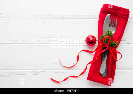 Table setting for celebration Christmas and New Year Holidays on white wooden table.. Festive place setting for christmas dinner with red napkin and n Stock Photo