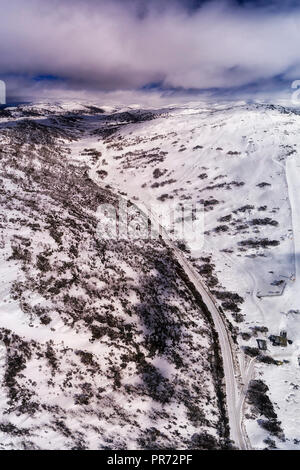 Ground to distant snow covered mountain peaks in Snowy mountains between PErisher valley town and Charlotte pass connected by unsealed icy road along  Stock Photo