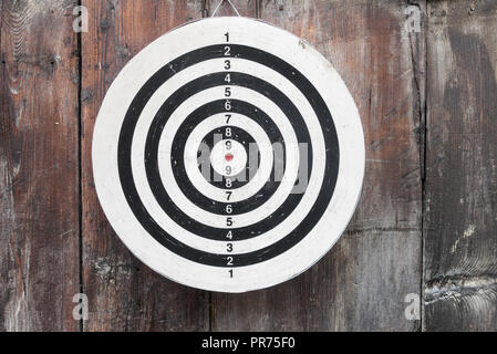round circular black and white target with numbers hanging on a wooden wall up close and in detail Stock Photo