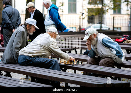 RIGA, LATVIA - SEPTEMBER 14, 2018: Men seated on park benches and playing chess. Stock Photo