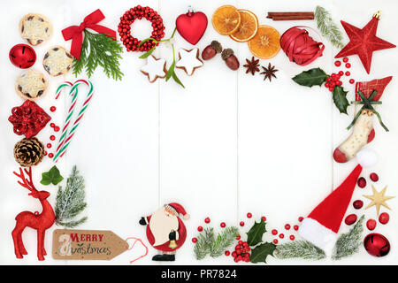 Christmas background border composition with traditional symbols of bauble tree decorations, candy canes, mince pies, fruit, spices & winter flora. Stock Photo