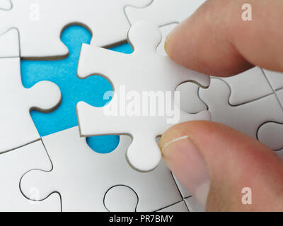 Closeup hand placing last piece of puzzle Stock Photo